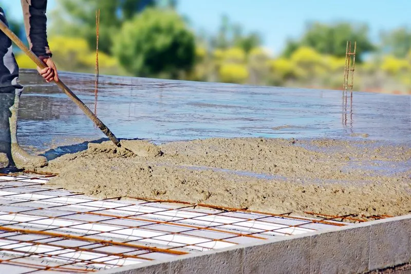 Concrete worker screeding a freshly poured reinforced concrete slab