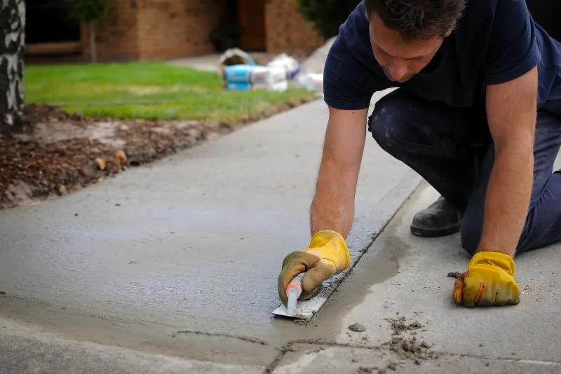 Tradesperson smoothing freshly resurfaced concrete on a Gold Coast driveway