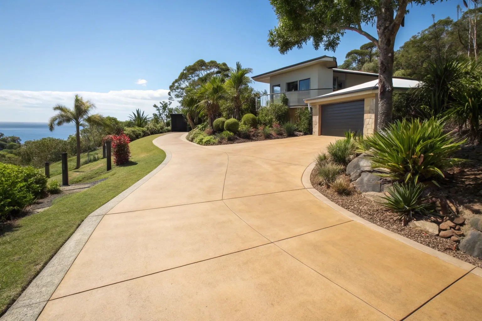 Coloured concrete driveway in warm sandstone finish outside a modern Gold Coast home